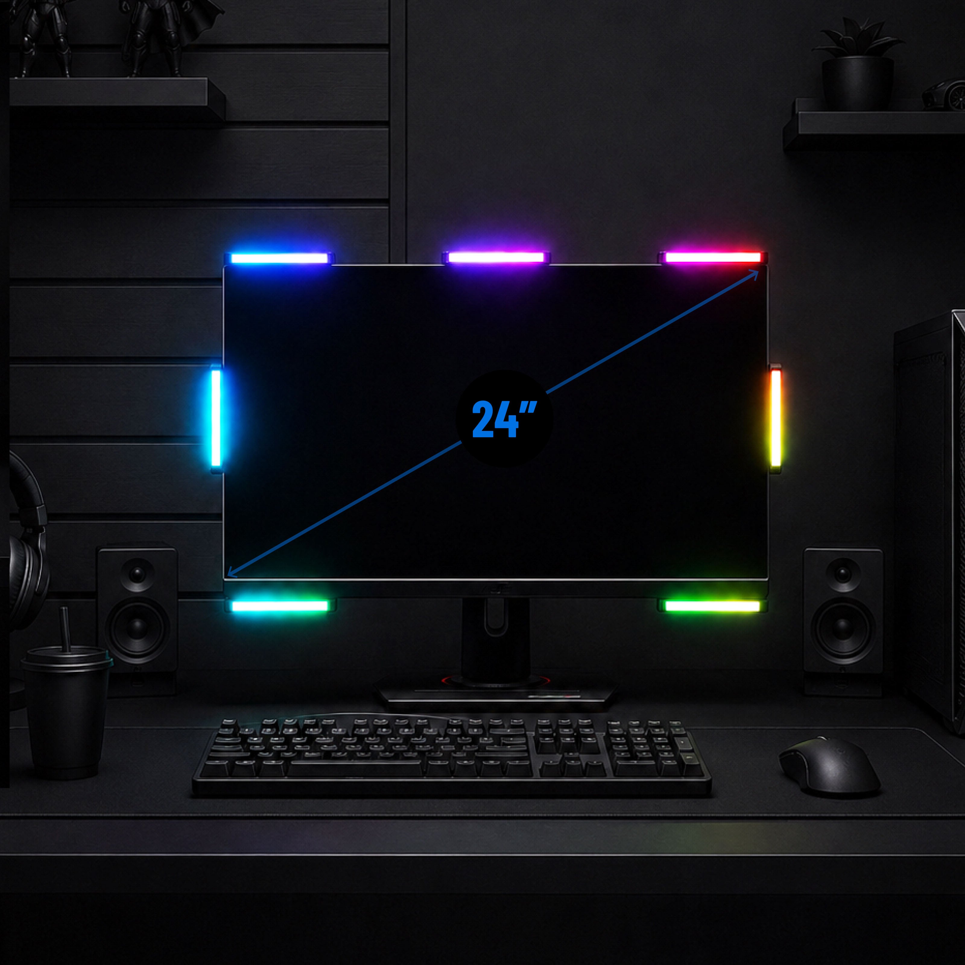 A 24-inch computer monitor with colorful LED light strips around its edges, shown on a dark desk with a keyboard, mouse, speakers, and headphones in a gaming setup.